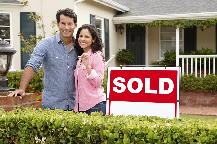 New Homeowners Standing in Front of Home with Keys